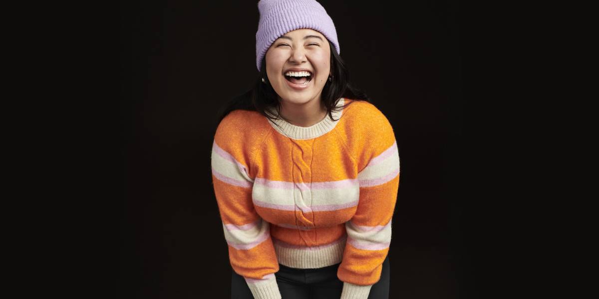 Woman wearing an orange and cream striped knit. Shop knitwear